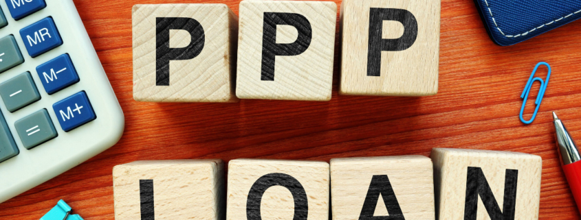 Tiles with PPP LOAN spelled out on a desk with office accessories