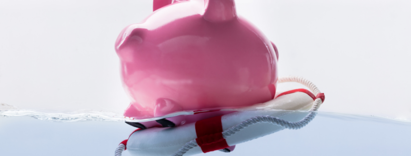 Pink piggy bank on a life saver in the water