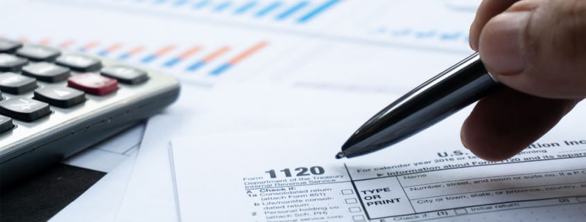 Close up of accountant going over tax documents with a pen and calculator