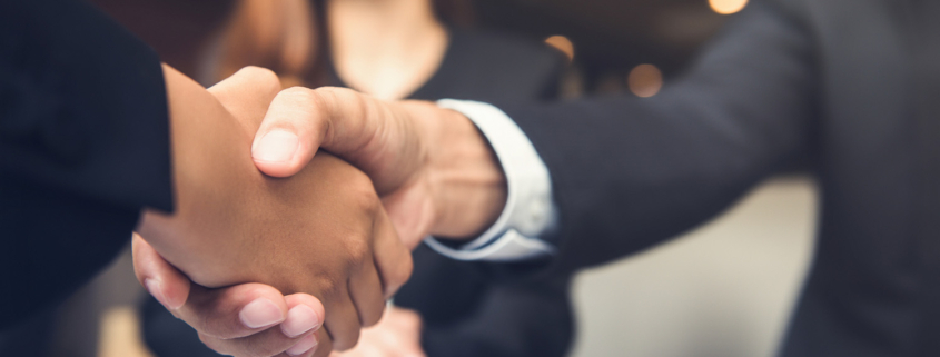 client and agent shake hands with client's female partner blurred out in bg
